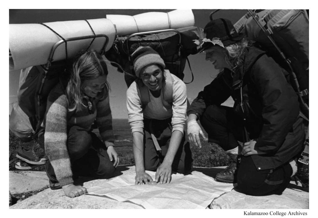 Three individuals with backpacks gather around to read a map.