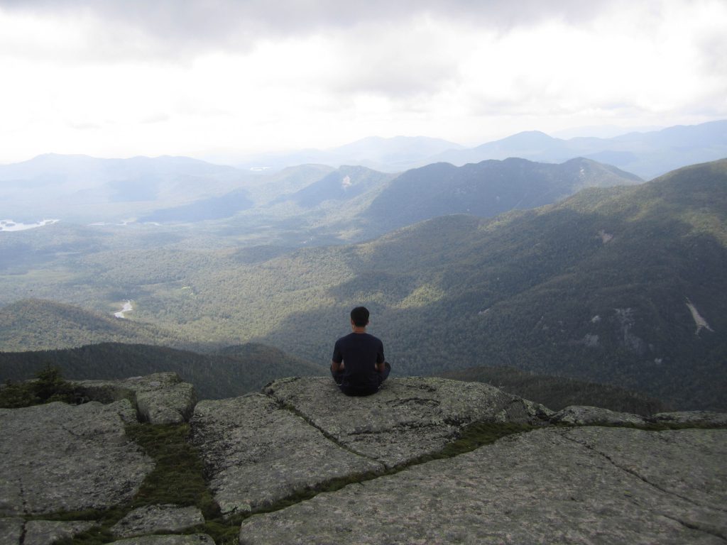 An individuals sits alone atop an Adirondaks summit. 