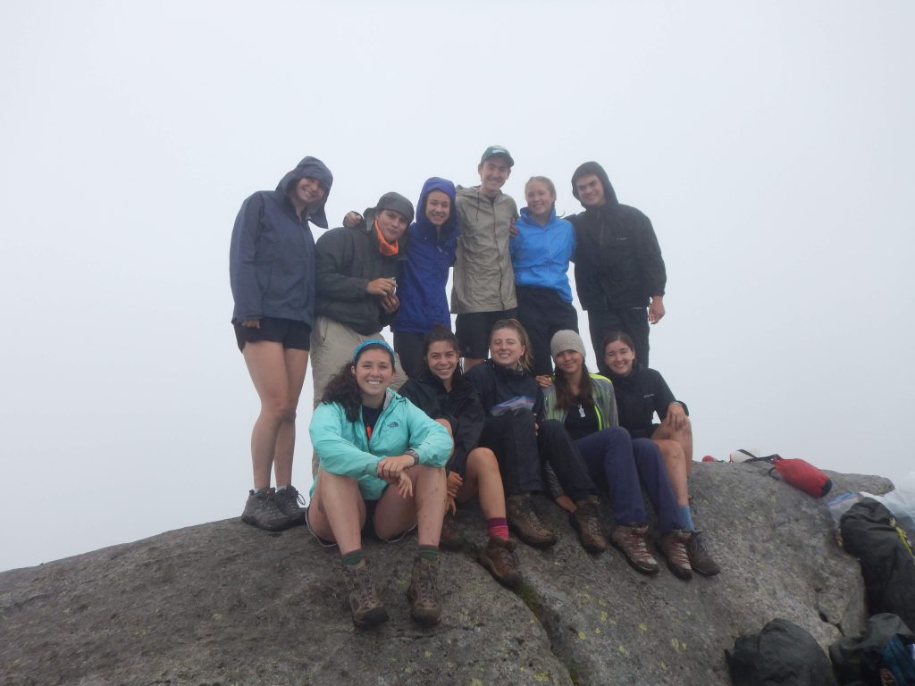 A group poses atop a cloudy summit. 