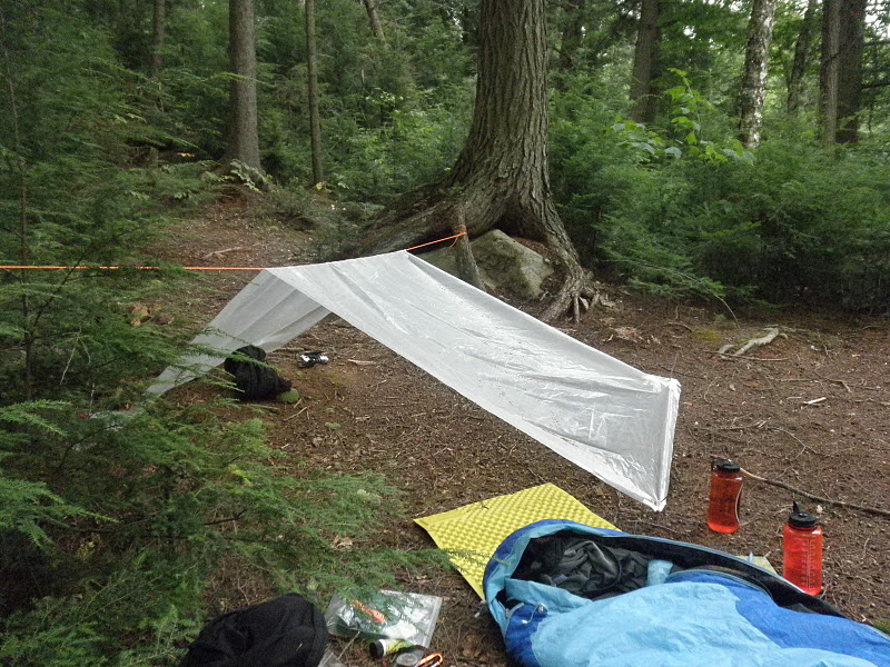 An individuals solo location fit with a set-up tarp, sleeping pad, and sleeping bag. 