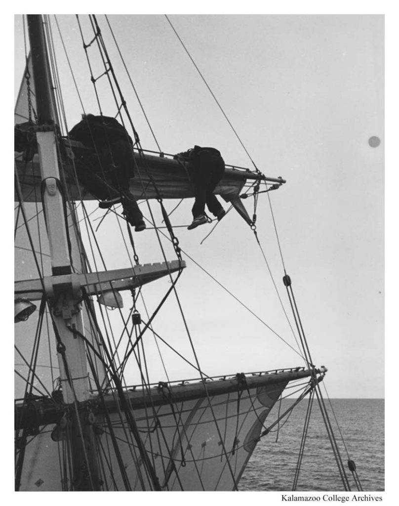 Two individuals hang over the side of the playfair's mast. 