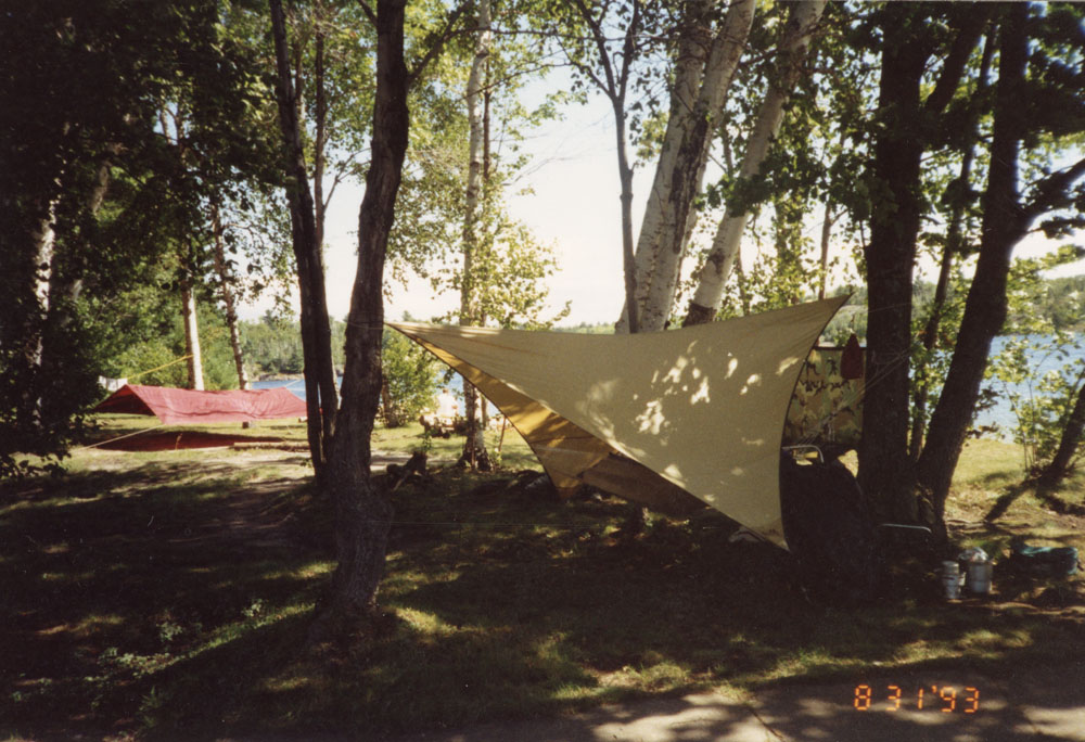 A yellow tarp is set up between some trees.