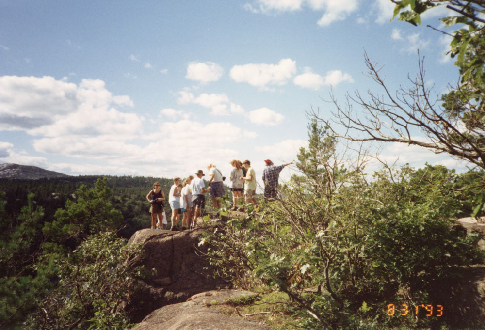 A group gathers at the top of a peak. 