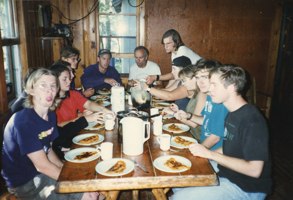 A group of leaders and the directors enjoy a meal in the cabin.